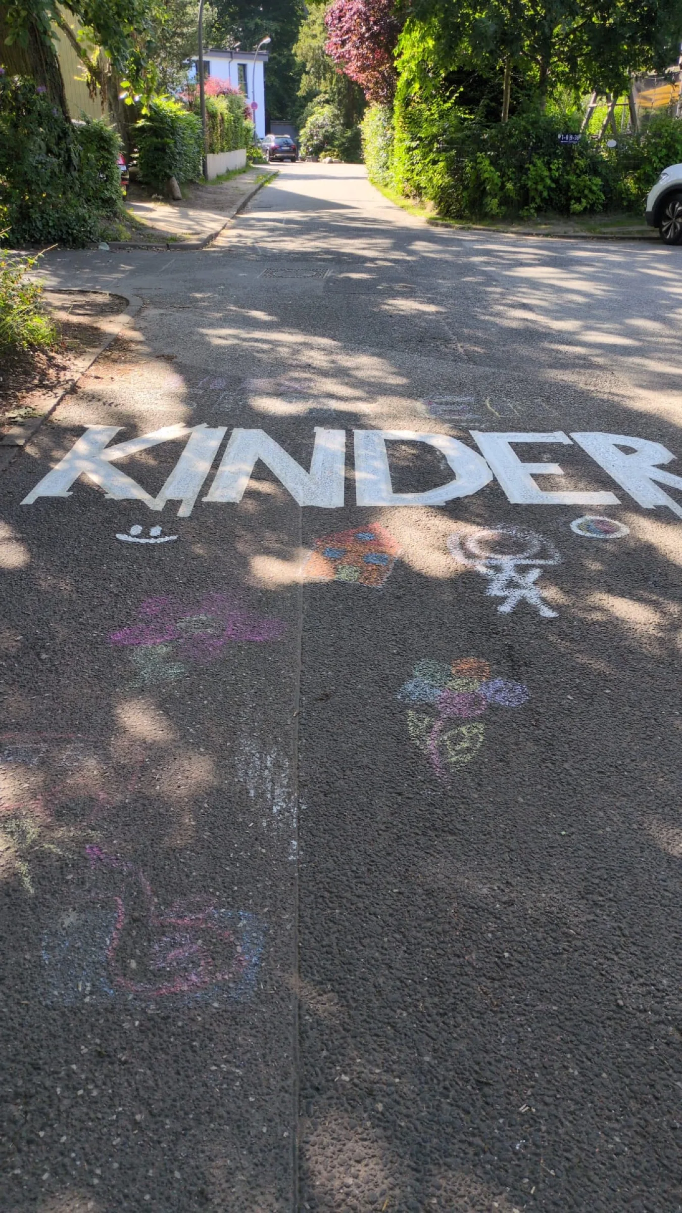 Mit bunter Kreide hat jemand KINDER auf das Pflaster des Pikartenkamps geschrieben, daneben kleine Straßenkreide-Zeichnungen